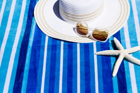 Summer hat with sunglasses on a beach towel.の写真素材