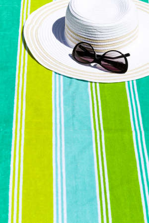 Summer hat with sunglasses on a beach towel.の写真素材