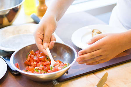 Kinds in cooking class making bruschetta.の写真素材