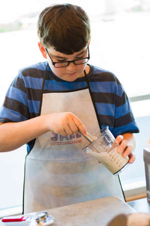 Kid in cooking class learning how to cook and bake.の写真素材