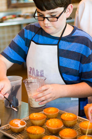 Kid in cooking class learning how to cook and bake.の写真素材