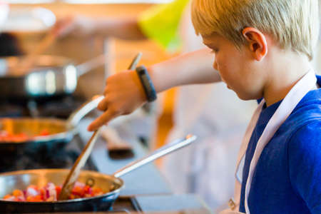 Kids learning how to cook in a cooking class.の写真素材