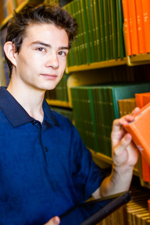 College student with computer tablet in campus library.