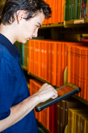 College student with computer tablet in campus library.