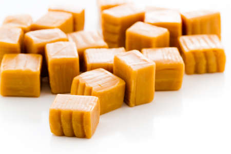 Vanilla caramel candy unwrapped on a white background.の写真素材