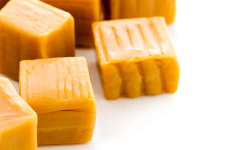 Vanilla caramel candy unwrapped on a white background.の写真素材