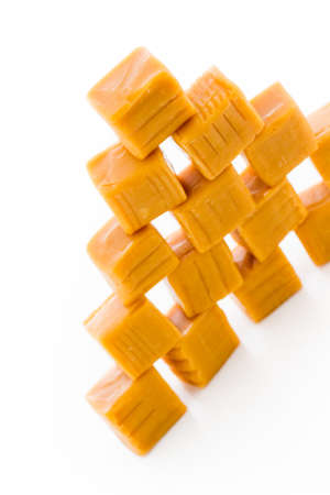 Vanilla caramel candy unwrapped on a white background.の写真素材