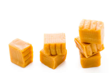Vanilla caramel candy unwrapped on a white background.の写真素材