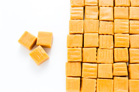 Vanilla caramel candy unwrapped on a white background.の写真素材