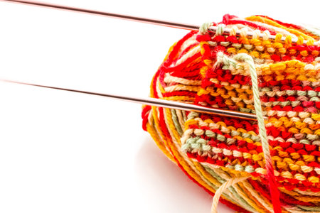 Knitting with multi colored yarn with orange, red, and yellow tones.