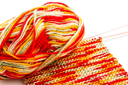 Knitting with multi colored yarn with orange, red, and yellow tones.