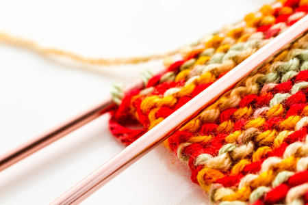 Knitting with multi colored yarn with orange, red, and yellow tones.