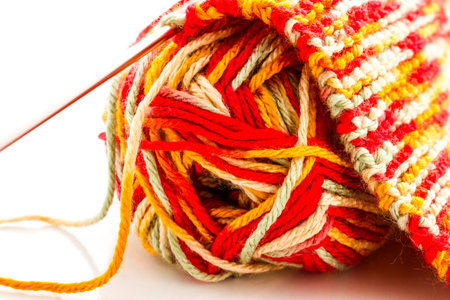 Knitting with multi colored yarn with orange, red, and yellow tones.