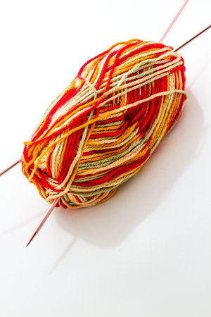 Knitting with multi colored yarn with orange, red, and yellow tones.