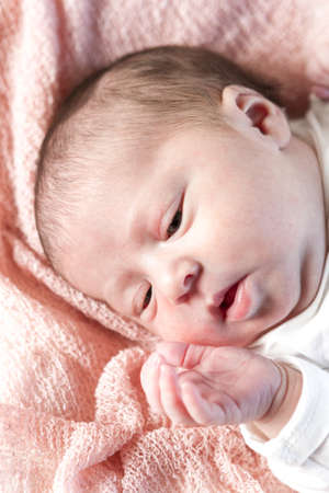 Newborn baby girl playing on pink blanket.の写真素材