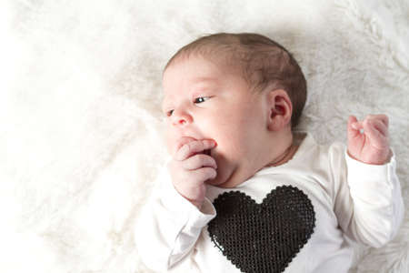 Newborn baby girl playing on a white blanket.の写真素材