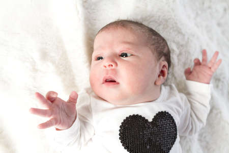 Newborn baby girl playing on a white blanket.の写真素材