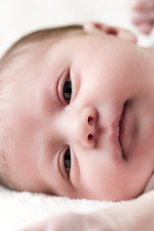 Newborn baby girl playing on a white blanket.