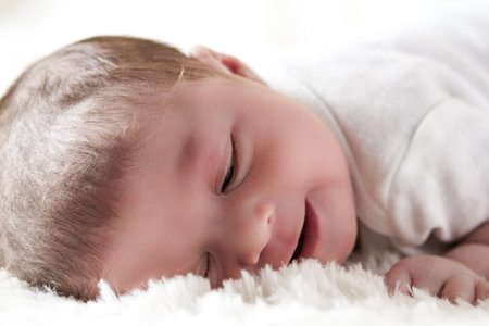 Newborn baby girl playing on a white blanket.