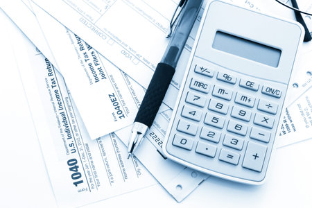 Calculating numbers for income tax return with pen and calculato