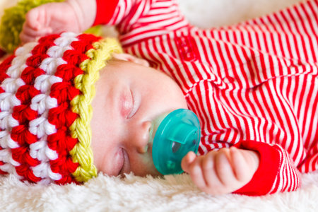 Newborn Christmas baby girl in elf hat on a white blanket.の写真素材
