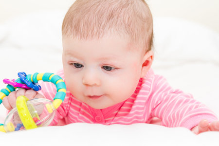 Newborn baby girl playing on a white blanket.の写真素材