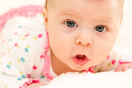 Baby girl playing on a white blanket.の写真素材