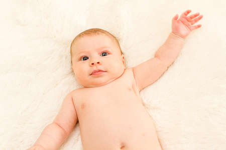 Baby girl playing on a white blanket.の写真素材