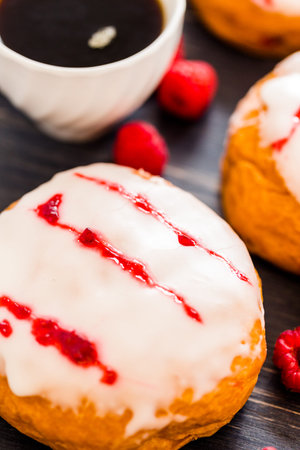 Fresh raspberry jelly filled donuts with white glazing on top.の写真素材