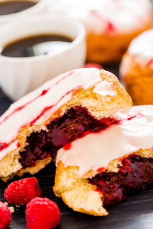 Fresh raspberry jelly filled donuts with white glazing on top.