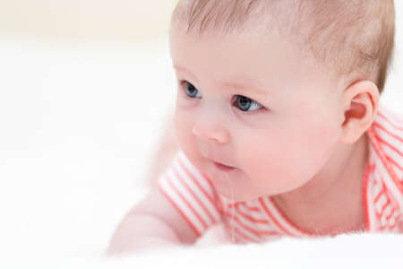 Infant baby girl playing on a white blanket.の写真素材