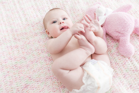 Infant baby girl playing on a pink blanket.