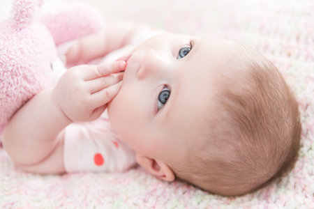 Infant baby girl playing on a pink blanket.の写真素材