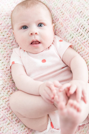 Infant baby girl playing on a pink blanket.