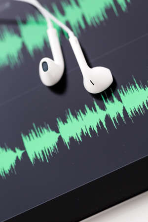 white headphones on top of computer tablet.の写真素材