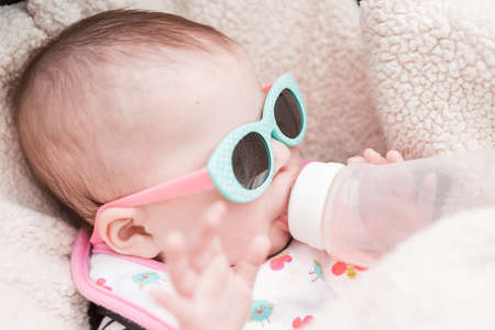 Cute baby girl wearing cute sunglasses in a car seat.の写真素材