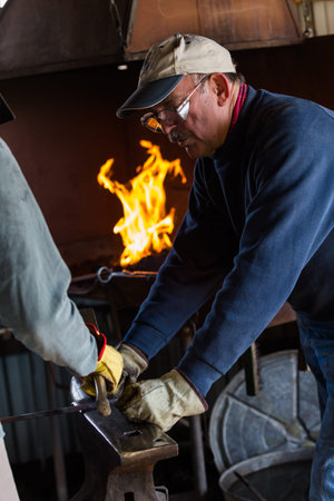 A blacksmith teaching his students to old craft.
