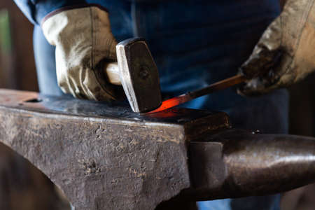 A blacksmith forging hot iron on the anvil.の写真素材