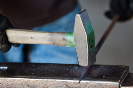 A blacksmith forging hot iron on the anvil.