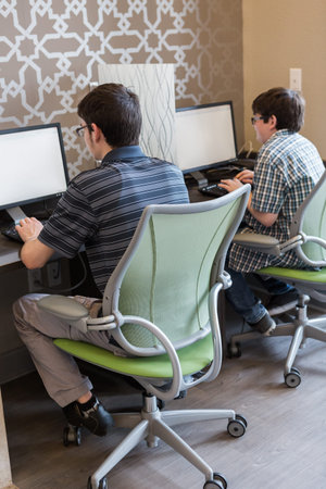 Teenage brothers playing with their computer gadgets at leisure time.