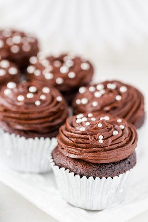 Gourmet chocolate cupcakes decorated with silver balls on chocolate icing.の写真素材