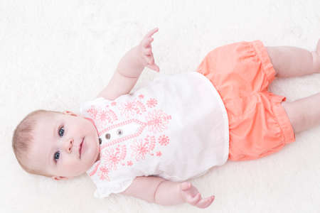 Cute baby girl playing on a white blanket.の写真素材