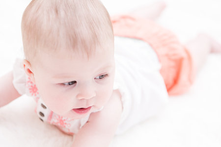 Cute baby girl playing on a white blanket.