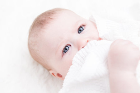 Cute baby girl playing on a white blanket.
