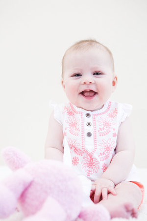 Baby girl playing with her toys on a white blanket.の写真素材