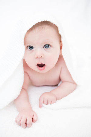 Cute baby girl playing on a white blanket.の写真素材