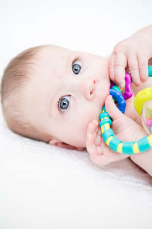 Cute baby girl playing on a white blanket.の写真素材