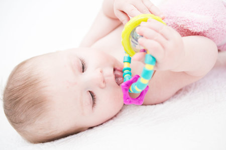 Cute baby girl playing on a white blanket.