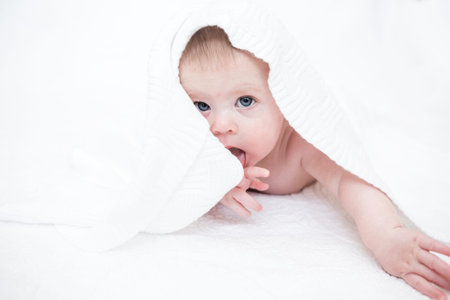 Cute baby girl playing on a white blanket.の写真素材