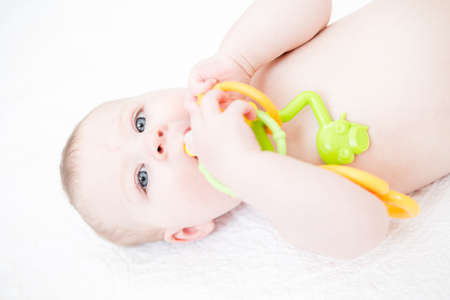 Cute baby girl playing on a white blanket.の写真素材